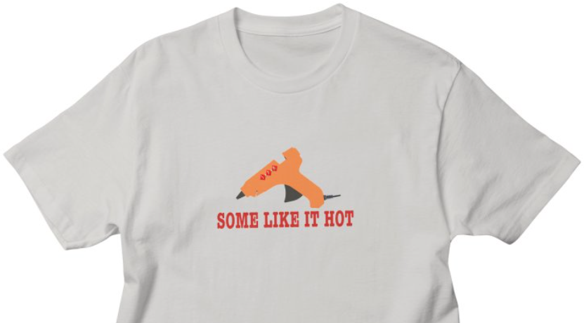 A gray t-shirt with a drawing of a hot glue gun and the slogan "Some like it hot"