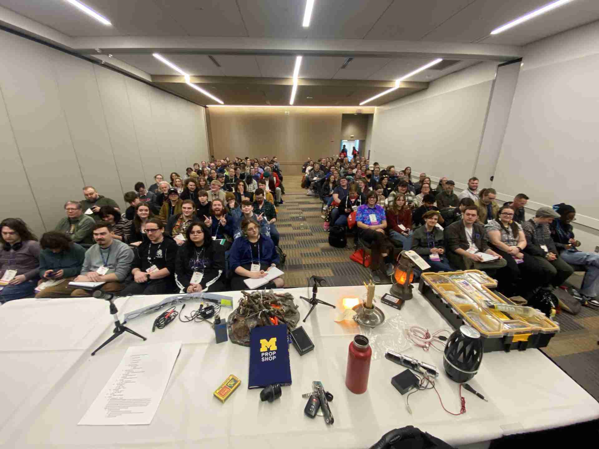 A picture of the workshop attendees all facing the table of props