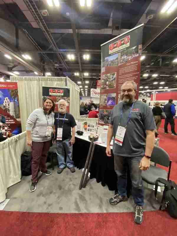 SPM Members Jordan Anderson, Jim Guy, and Ben Hohman, smiling in the S*P*M booth